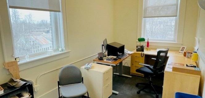 View of office, with desk, whiteboard, computer, and bookshelves with lots of light from windows. 